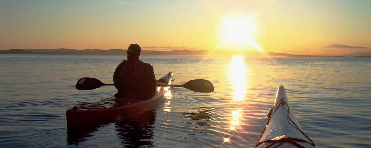 Kayakers floating at sunset
